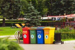 Contenedores de basura de distintos colores para clasificar los residuos, ubicados en un parque.
