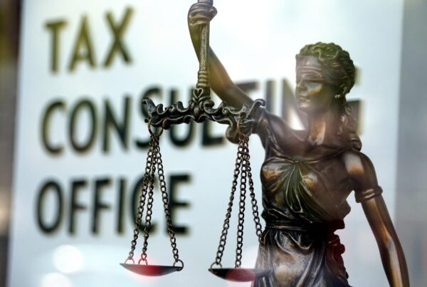 Figura de justicia y en el fondo se aprecia una pared que pone "TAX CONSULTING OFFICE"